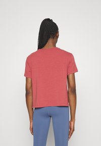 Camiseta roja de manga corta con cuello redondo, hecha de una tela suave y ligera. Diseño recortado con un ajuste holgado.