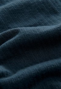Dunkelblauer Stoff mit einer weichen, gerippten Textur, der subtile Farbvariationen und feine, horizontale Linien aufweist. Glatt und leicht elastisch.