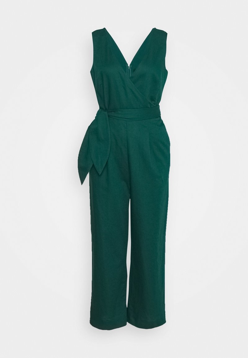 Combinaison sans manches vert foncé avec encolure en V, corsage style portefeuille, ceinture nouée à la taille et pantalon à jambes larges sur fond uni.
