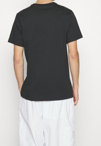Černé bavlněné tričko s krátkým rukávem a kulatým výstřihem, které má jednoduchý design a volný střih. Žádné výrazné vzory ani akcenty.