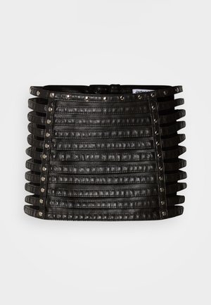 Zwarte leren minirok met horizontale riemdetails en zilveren studs langs de bovenrand en verticale zijden.