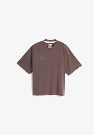 Brun bomull T-skjorte med korte ermer, avslappet passform og rund hals; har et lite brodert design på øvre venstre brystområde.