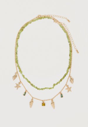Deux colliers superposés, l'un avec de petites pierres vertes, l'autre en or avec des breloques sur le thème de la mer et des pierres précieuses vertes et jaunes.