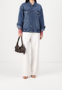 Dżinsowa kurtka z zapięciem na guziki, przednimi kieszeniami i szerokimi rękawami, noszona na czerwonej koszuli w kratę. Połączona z białymi spodniami typu szerokie nogawki i brązową torbą.