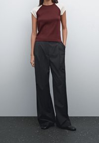 Maroon og creme farveblokeret kortærmet top kombineret med stribede vide bukser; glat tekstur; minimalistisk design; sorte sko.