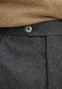 Gråullbyxor har en enkel knappstängning, skarpa veck och en mjuk textur, ihop med en beige stickad topp.