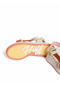 Sandalia con parte superior en gris y rosa, que cuenta con correas ajustables y suela de goma. La suela tiene un patrón de espiga y el logo "Hoff".
