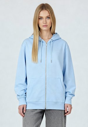 Felpa con zip di colore azzurro chiaro, dotata di cappuccio regolabile, tasche frontali e polsini a costine. Realizzata in tessuto morbido e textured.