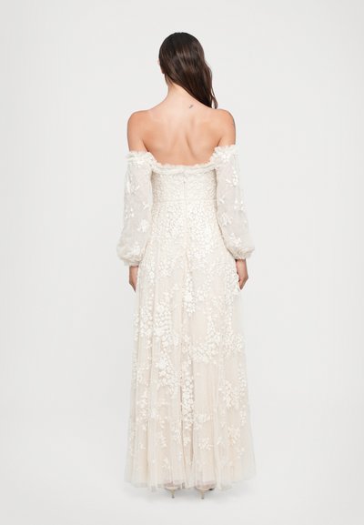 Vestido de tul marfil, con escote off-the-shoulder y mangas largas, adornado con bordados florales y una falda fluida. Cuerpo ajustado con detalle texturizado.
