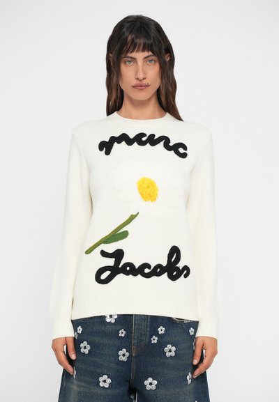 Pulover alb din tricot cu un motiv mare de margaretă, având un centru galben și un tulpină verde, alături de "Marc Jacobs" brodat cu fir negru.