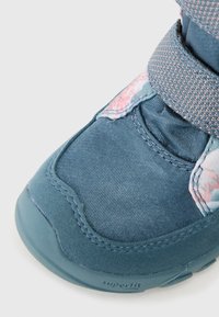 Modrá dětská bota s vzorovaným textilním svrškem, suchým zipem a gumovou podrážkou. Má texturovaný povrch a zesílenou špičku.