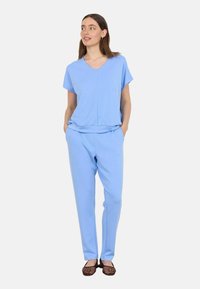 Light blue lounge set featuring a short-sleeve V-neck top and matching tapered pants, made of soft, lightweight fabric with side pockets.
