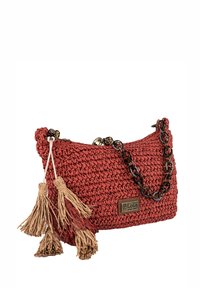 Bolso de mano tejido rojo con un acabado texturizado, que presenta una cadena como asa y dos borlas en tono beige. Incluye un parche con el logo en la parte frontal.