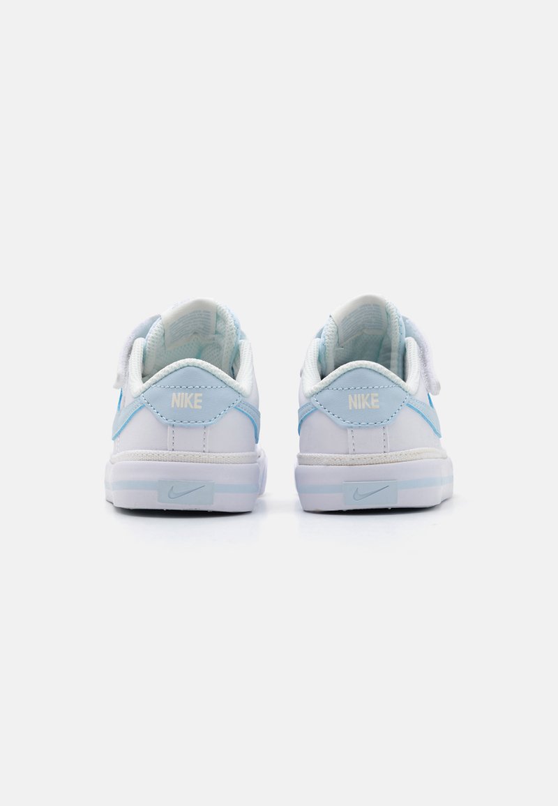 Zapatillas Nike con una combinación de colores blanco y azul claro, que presentan una parte superior de cuero liso, un collar acolchado y el logo característico en el talón.