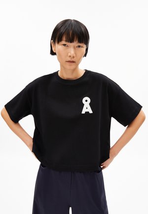 Black cropped t-shirt made of cotton; features a white letter "A" on the chest; short sleeves, relaxed fit, smooth texture.