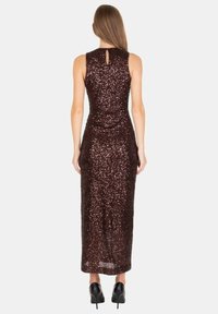 Abito lungo marrone in paillettes con silhouette aderente, scollatura alta e dettaglio a chiave sulla schiena. Massima lunghezza, texture liscia e superficie riflettente.