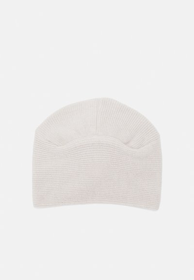 Knitted beanie in light beige, featuring a ribbed texture and a rounded top. No visible brand markings or embellishments.