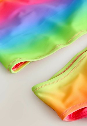 Färgglad simdräkt med en mjuk, sträcker sig textur. Har ett gradientmönster i rosa, blått, grönt och orange. Kanterna har synlig sömnad.