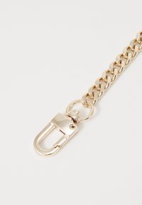 Metal kæde i guld tone, med sammenflettede led. Bemærkelsesværdig drejefastgørelse med hængslet lås, glat tekstur, minimalistisk design.