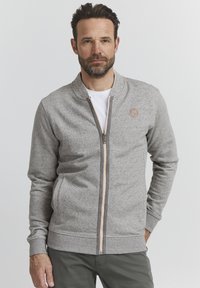 Graues Zip-Hoodie mit strukturiertem Finish, gerippten Bündchen und Saum sowie einem kleinen Logo auf der linken Brust. Verfügt über einen kontrastierenden Reißverschluss.