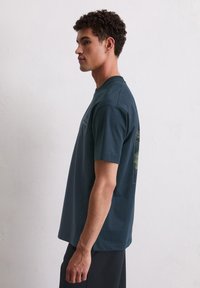 Navyblaue Baumwoll-T-Shirt mit kurzen Ärmeln, Rundhalsausschnitt und grafischen Details auf der Rückseite, ausgestattet mit einer dezenten, strukturierten Optik.