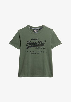 Camiseta de algodón color verde oliva con mangas cortas, escote redondo y estampado negro que presenta el diseño de texto 'Vintage SuperDry' y 'Premium Goods'.