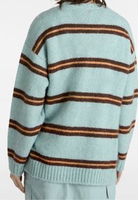 Maglione oversize di colore azzurro chiaro con righe verticali marroni e arancioni. Morbido tessuto a maglia, orlo a costine e vestibilità comoda.