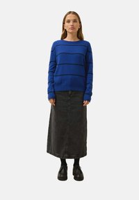 Blårandig tröja med rund hals, parat med en lång svart denimkjol. Svarta skor fulländar outfiten.