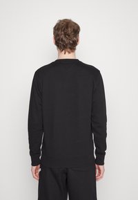 Sudadera negra de manga larga, con puños y dobladillo acanalados, escote redondo y un diseño simple, que muestra una textura lisa y sólida.