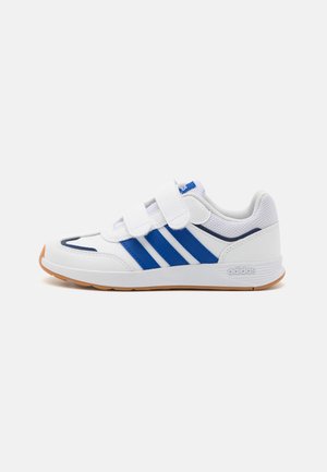 Scarpa da ginnastica bianca con strisce blu, caratterizzata da un design con cinturino in Velcro e una suola testurizzata. Logo del marchio visibile sul tallone.