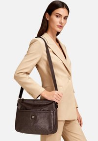 Borsa a tracolla in pelle marrone con finitura testurizzata, dotata di chiusura superiore con cerniera, tracolla regolabile e tasca frontale con dettaglio logo.