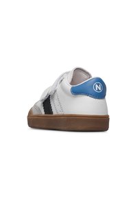 Sneaker bianco con inserti blu sul tallone, striscia nera di lato, suola in gomma marrone e fascia in Velcro, vista dall'angolo posteriore sinistro.