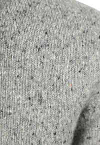 Gray knitted fabric with a textured pattern, featuring specks of white, black, and subtle purple hues. Soft, warm appearance.