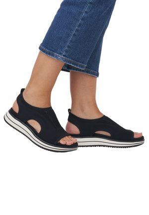 Black mesh sandals with open toes and cut-out sides, featuring a white midsole and textured black outsole for grip.