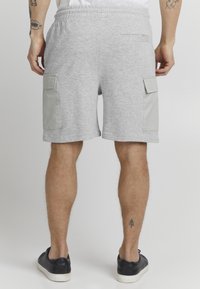 Shorts gris en mélange de coton avec taille élastique, poches cargo latérales et une poche à l'arrière. Texture lisse et design à longueur de genou.