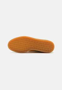 Talpa de sneaker din cauciuc cu un model texturat, având forme hexagonale; predominant portocalie cu câteva accente de verde închis pe margine.