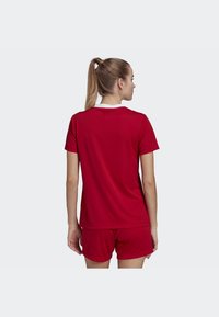 Punainen urheilupaita lyhyillä hihoilla ja valkoisella kauluksella, yhdistettynä matching punaisiin shortseihin. Sileä, hengittävä kangas.