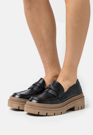 Mocassins en cuir noir avec une semelle plateforme épaisse marron. Doté d'un détail de sangle à l'avant et d'une semelle texturée. Design à bout rond.