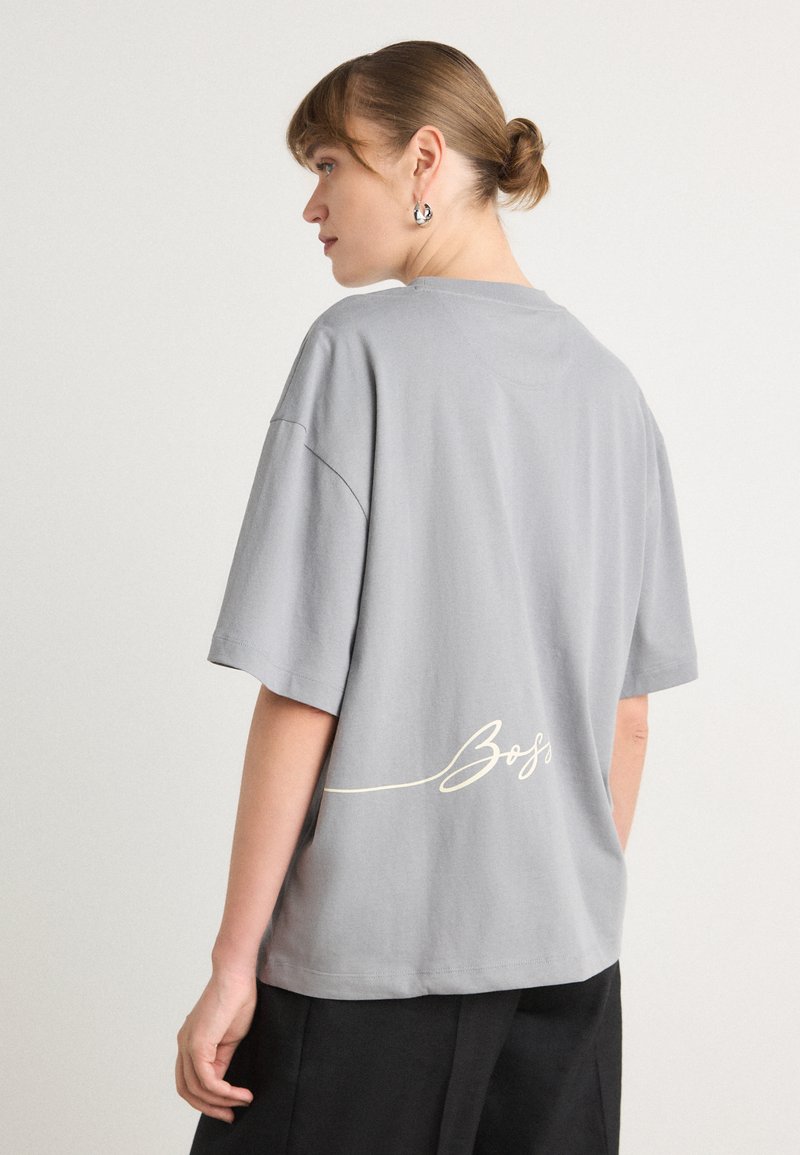 Grijze oversized T-shirt van katoen, met korte mouwen en een cursieve "Boss" opdruk op de achterkant. Zachte textuur, relaxte pasvorm.