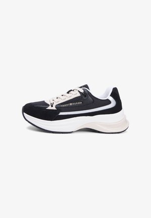 Αθλητικό παπούτσι σε μαύρο και μπεζ χρώμα με υφή στο επάνω μέρος, σουέντ λεπτομέρειες, λευκή μεσαία σόλα και διακοσμητικό λογότυπο στο πλάι.