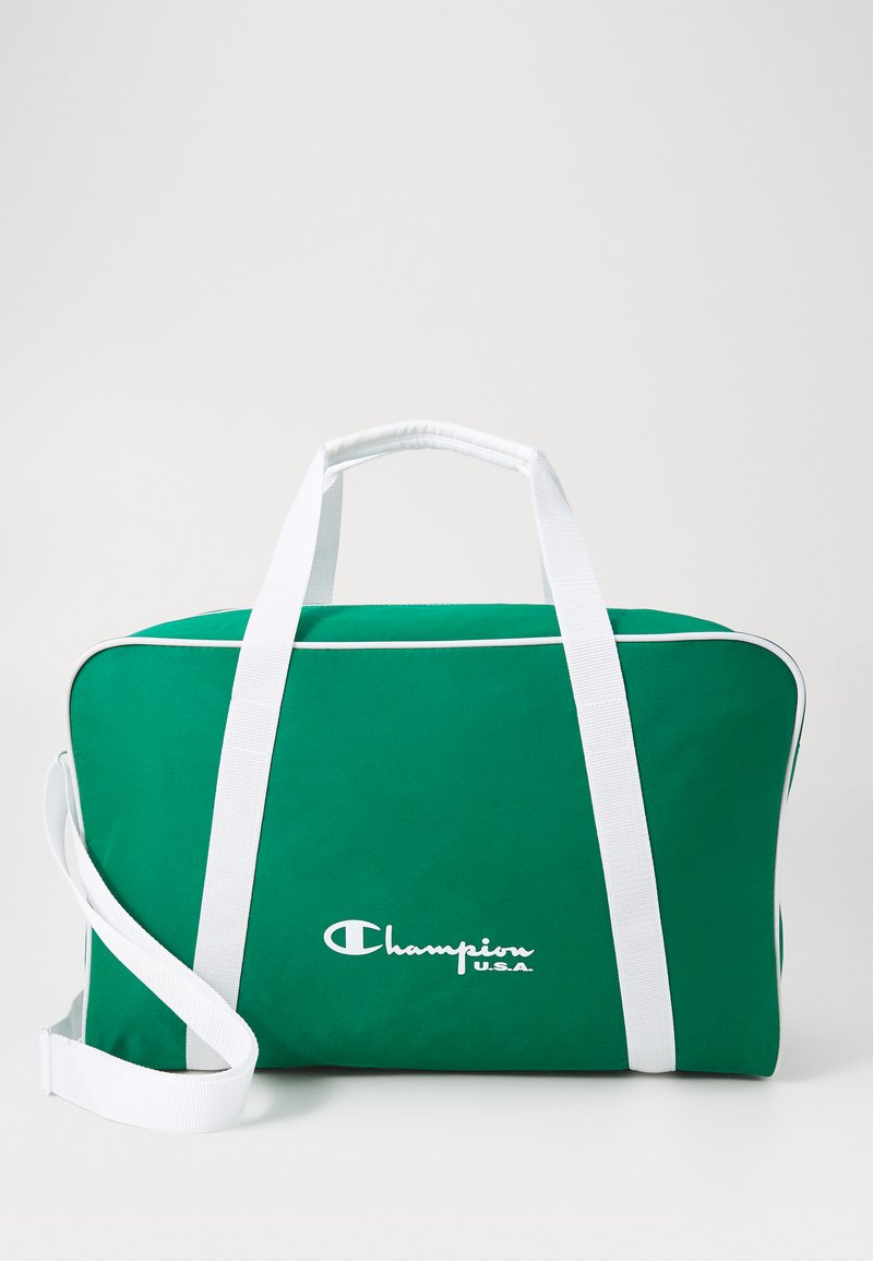 Bolso de deporte verde con acentos y correas blancas, fabricado con material duradero. Cuenta con un logo en blanco, textura suave y forma redondeada.