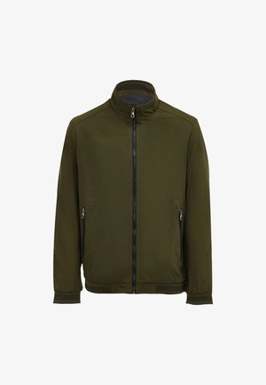 Jachetă de culoare verde măslinie, cu fermoar frontal, guler înalt, două buzunare laterale cu fermoar, manșete elastice și o textură de material neted, ușor.