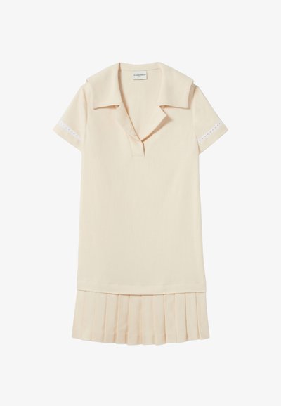 Robe beige pâle avec un col, des manches courtes et des détails en œillets aux poignets. Dotée d'un ourlet plissé. Texture de tissu lisse.