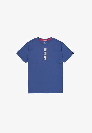 T-shirt à manches courtes et col rond en tissu bleu. Présente une étiquette verticale "ALPHA" en gris clair, avec des accents rouges sur le col.