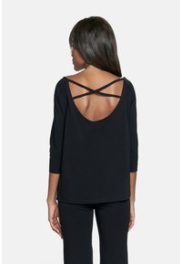 Czarne bluzki o luźnym kroju, z długimi rękawami i otwartym plecami z krzyżującymi się paskami. Miękki materiał o gładkiej fakturze.