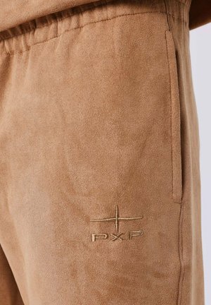 Tan suède broeken met een zachte textuur, een elastische taille, zijzak en een geborduurd "PXP"-logo in een subtiele tint die overeenkomt met de stof.