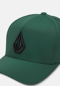 Gorra verde con un diseño estructurado, que presenta un logo negro, textura suave y acentos perforados para ventilación.