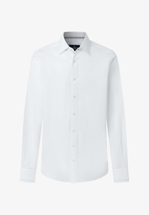 Weiße langärmlige Herrenhemd mit Knopfleiste und spitzem Kragen vor einfachem Hintergrund.