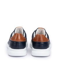 Granatowe skórzane buty z brązowym skórzanym akcentem na pięcie, białą gumową podeszwą i miękką podszewką wnętrza. Widok z tyłu ukazuje elegancki design.