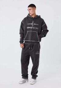 Conjunto de sudadera gris con pantalones de chándal a juego, hecho de una tela suave, con cremallera frontal, detalle de logo y costuras en contraste.